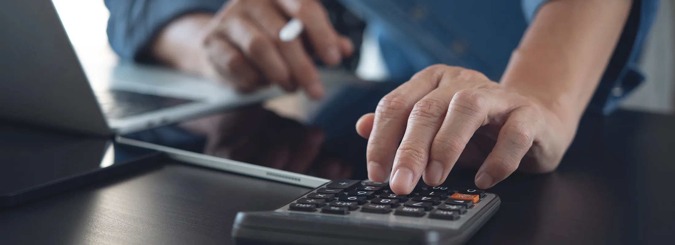 a person writing on a tablet device and using a calculator