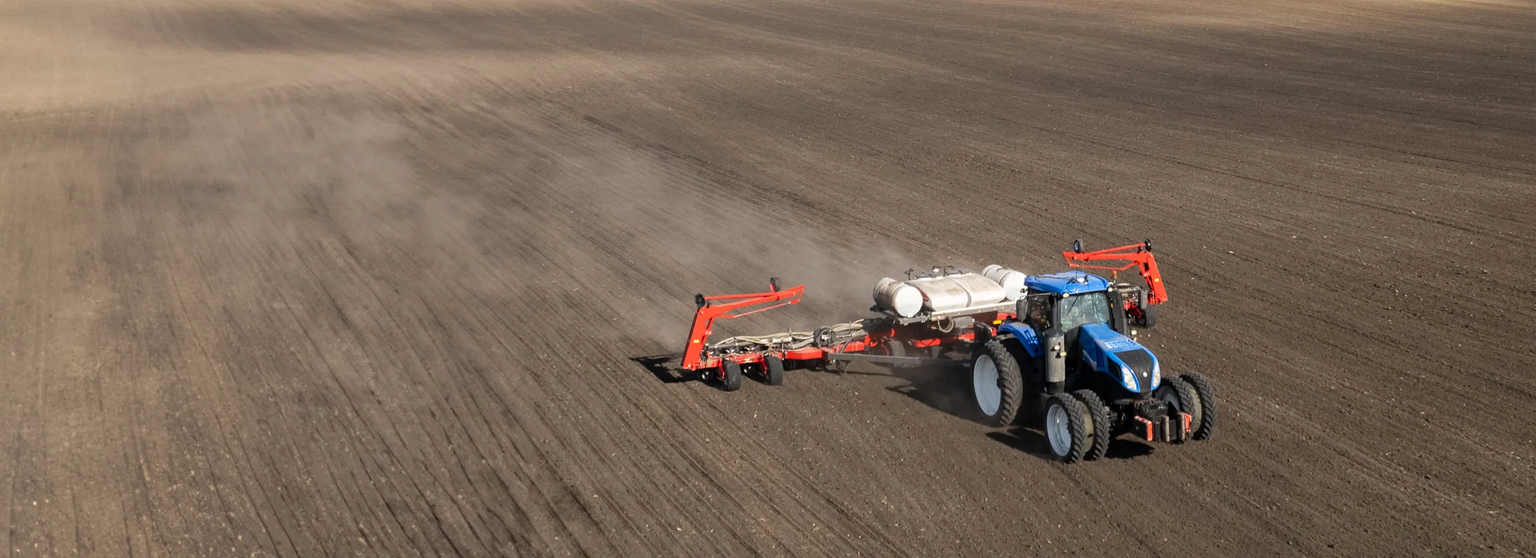 a tractor pulling a planter through a tilled field