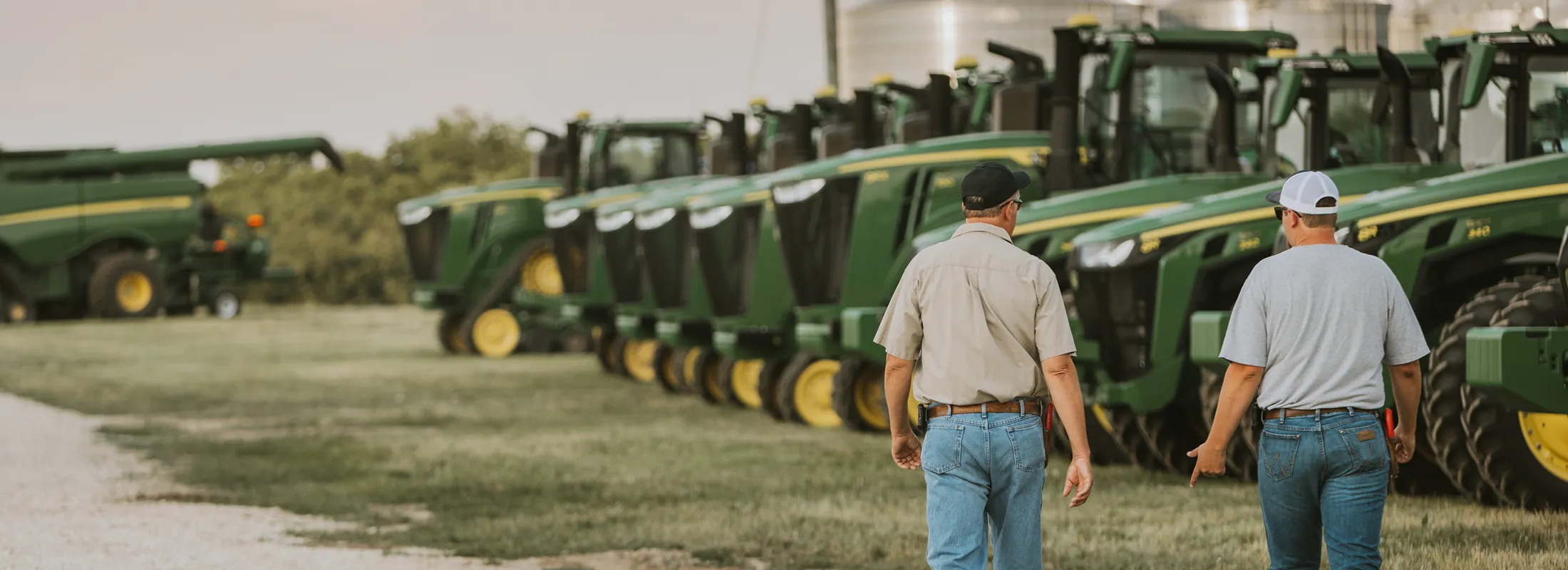 two men talking in front of a line of tractors