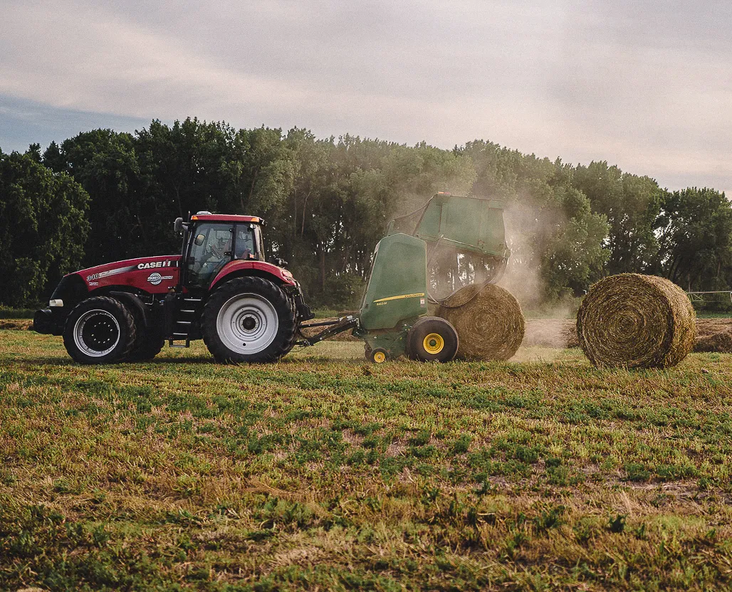 tractor and baler in field making hay bails